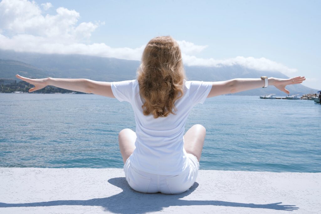 A woman overlooking the water with her arms outstretched. Her back is pain free and her health is better. Brookfield family chiropractor Chiropractor brookfield Chiropractor near me Holistic Chiropractic Chiropractic Care 