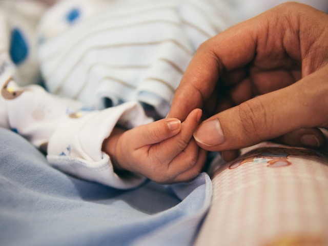 Parent holding a newborns hand