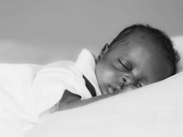Newborn baby sleeping on a white pillow.