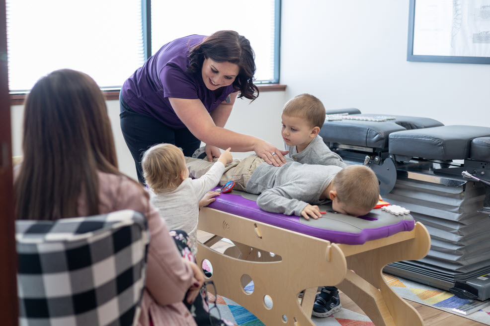 Dr. Nicole providing pediatric chiropractic care to children in a family-friendly clinic setting, with a focus on holistic health and wellness.