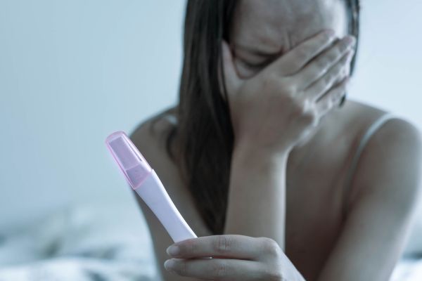 Woman feeling stressed and sad with a negative pregnancy test