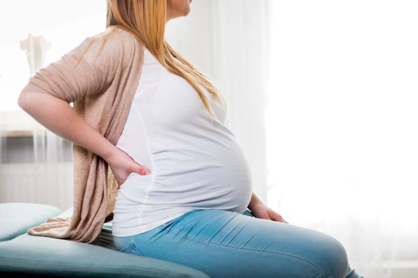 Woman on a chiropractic table who is pregnant feeling back pain