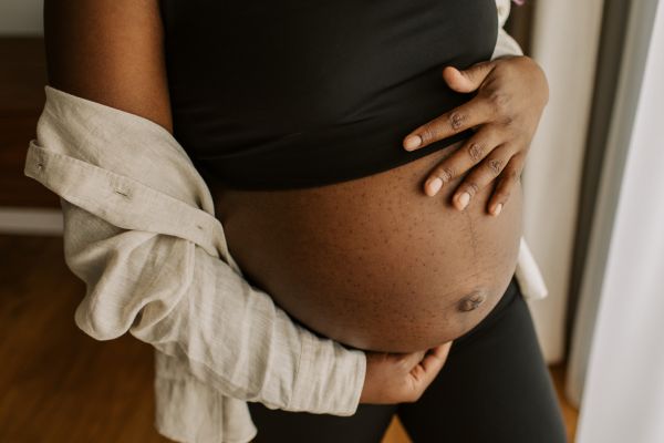 Woman of color holding pregnant belly